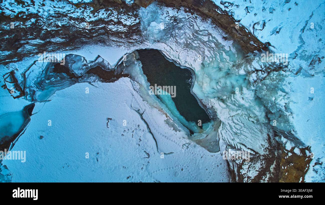 Luftgefrorener Wasserfall und Icy Pool mit schneebedeckter Landschaft Top Down Stockfoto