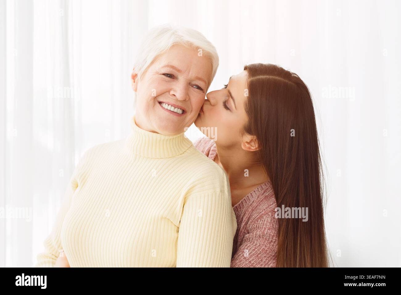 Junge Tochter küssen senior Mutter in der Backe Stockfoto