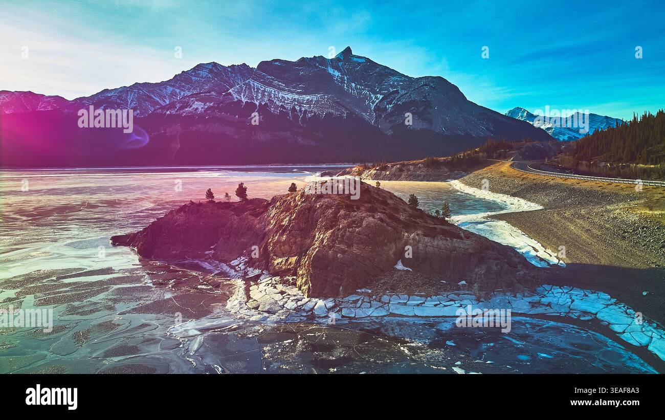 Der Rocky Aufschluss des Lake und die schneebedeckten Berge im Wintersonnenlicht Stockfoto