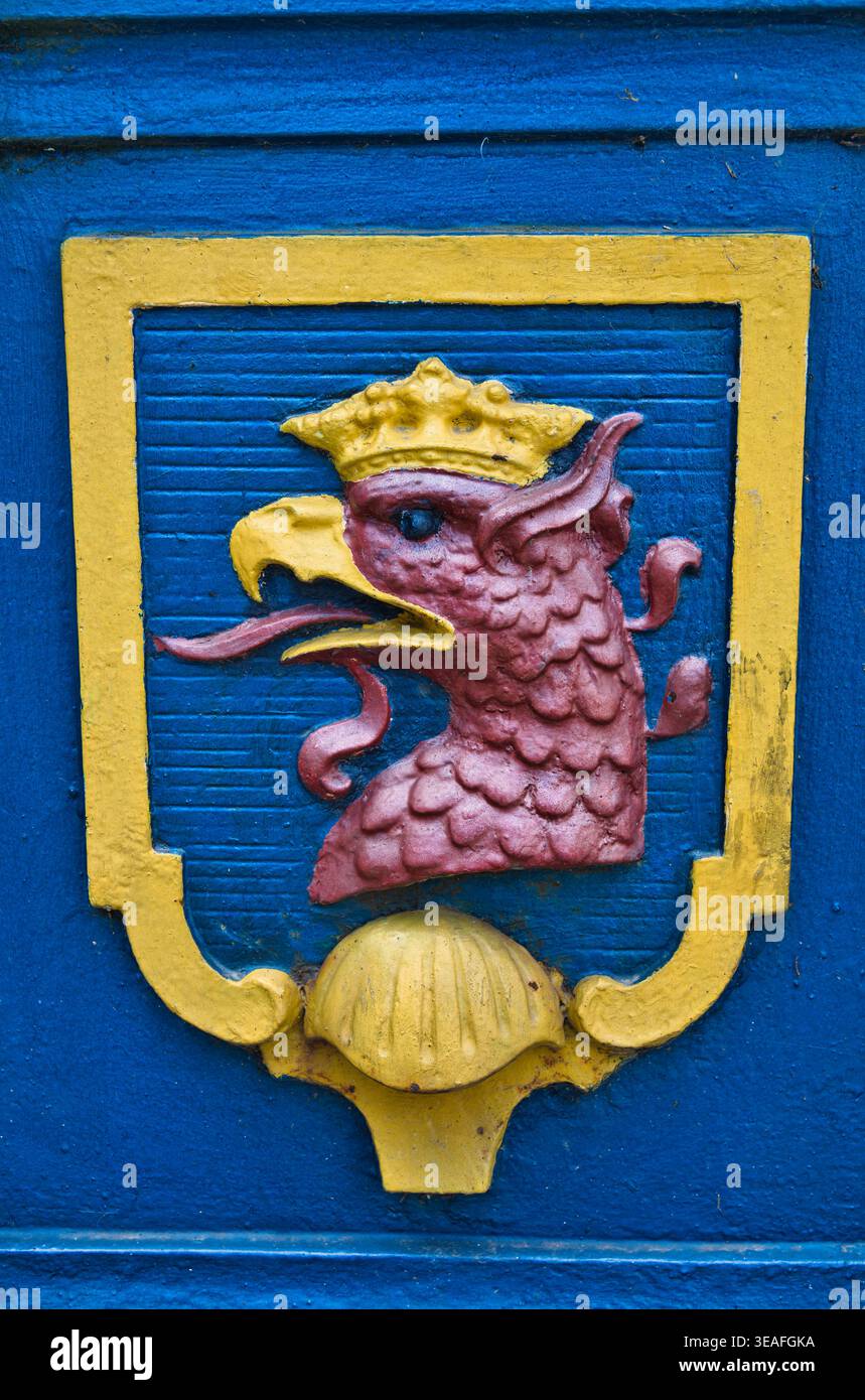 Bemalter Griffinkopf auf blauem Schild mit gelbem Rand und Kronenrelief - Stadt Szczecin. Stockfoto