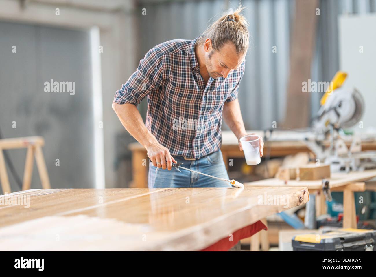 Mann, der Holz auf natürliche Holzplatten mit lebender Kante aufträgt Stockfoto