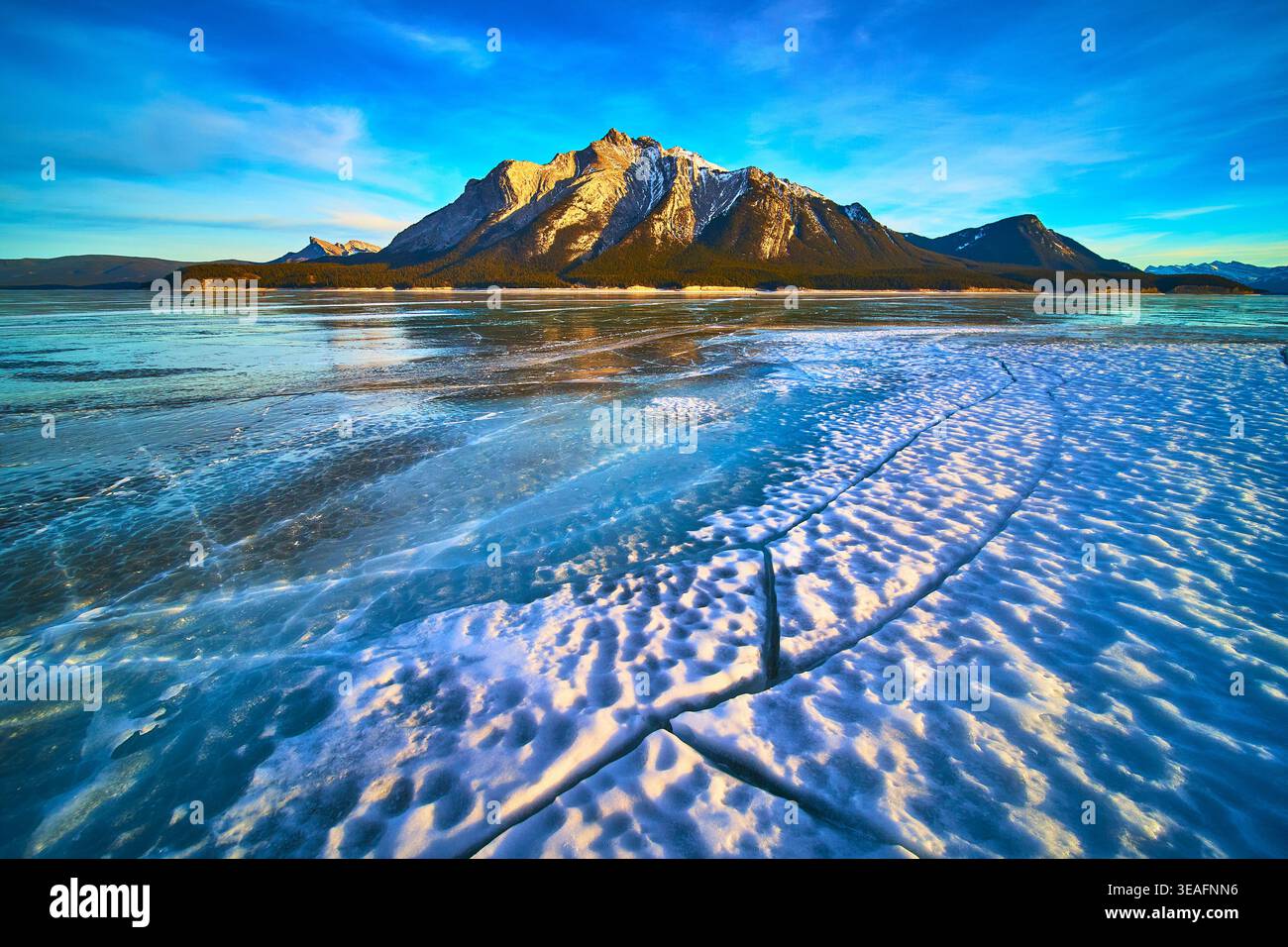 Gefrorene Seen und Schneemuster mit majestätischen Bergen im Winterlicht Stockfoto