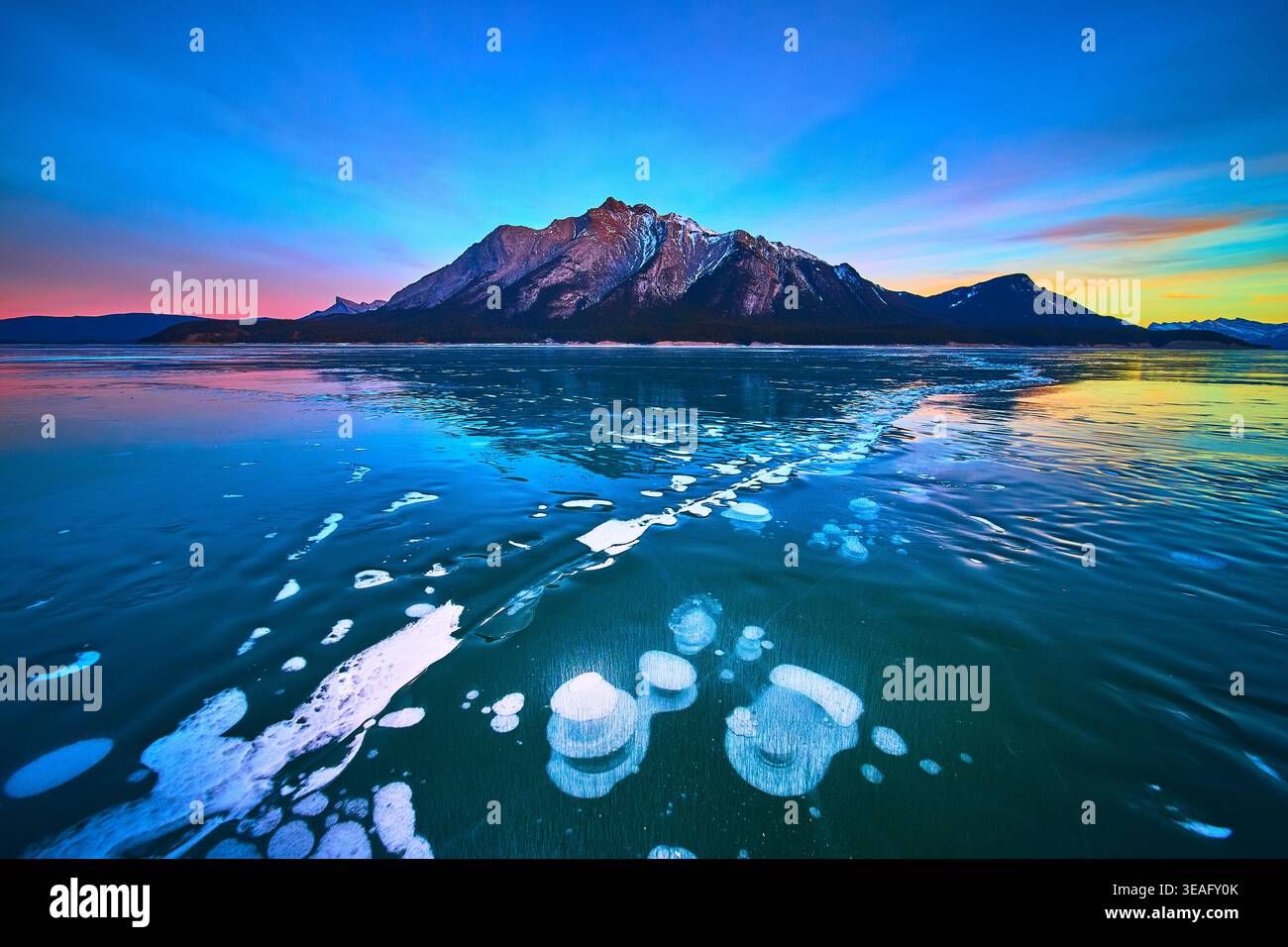 Frozen Lake Methan Bubbles und Mountain at Sunset im Winter Stockfoto