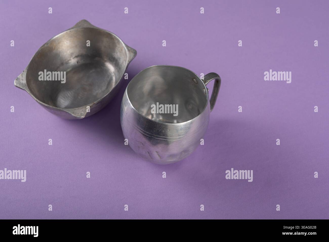 Nahaufnahme zeigt Schalen auf lila Oberfläche. Metall sorgt für Textur und diffuses Licht. Studio Shot hebt das Material hervor. Minimalistische Ästhetik, geeignet für Stockfoto