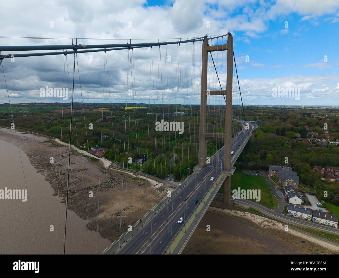 Aus der Vogelperspektive auf die Hängetürme der Humber Bridge und die Straße, die die Humber Mündung mit grünen Feldern und einem bewölkten Himmel in Kingston upon Hull, E, überspannt Stockfoto