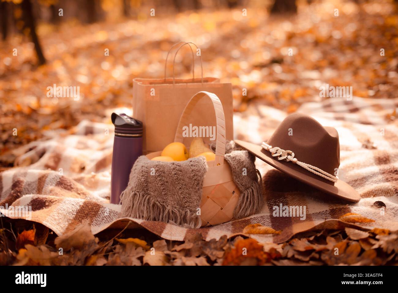 Herbststillleben mit wiederverwendbarer Flasche und Früchten auf dem Hintergrund goldener Blätter Stockfoto