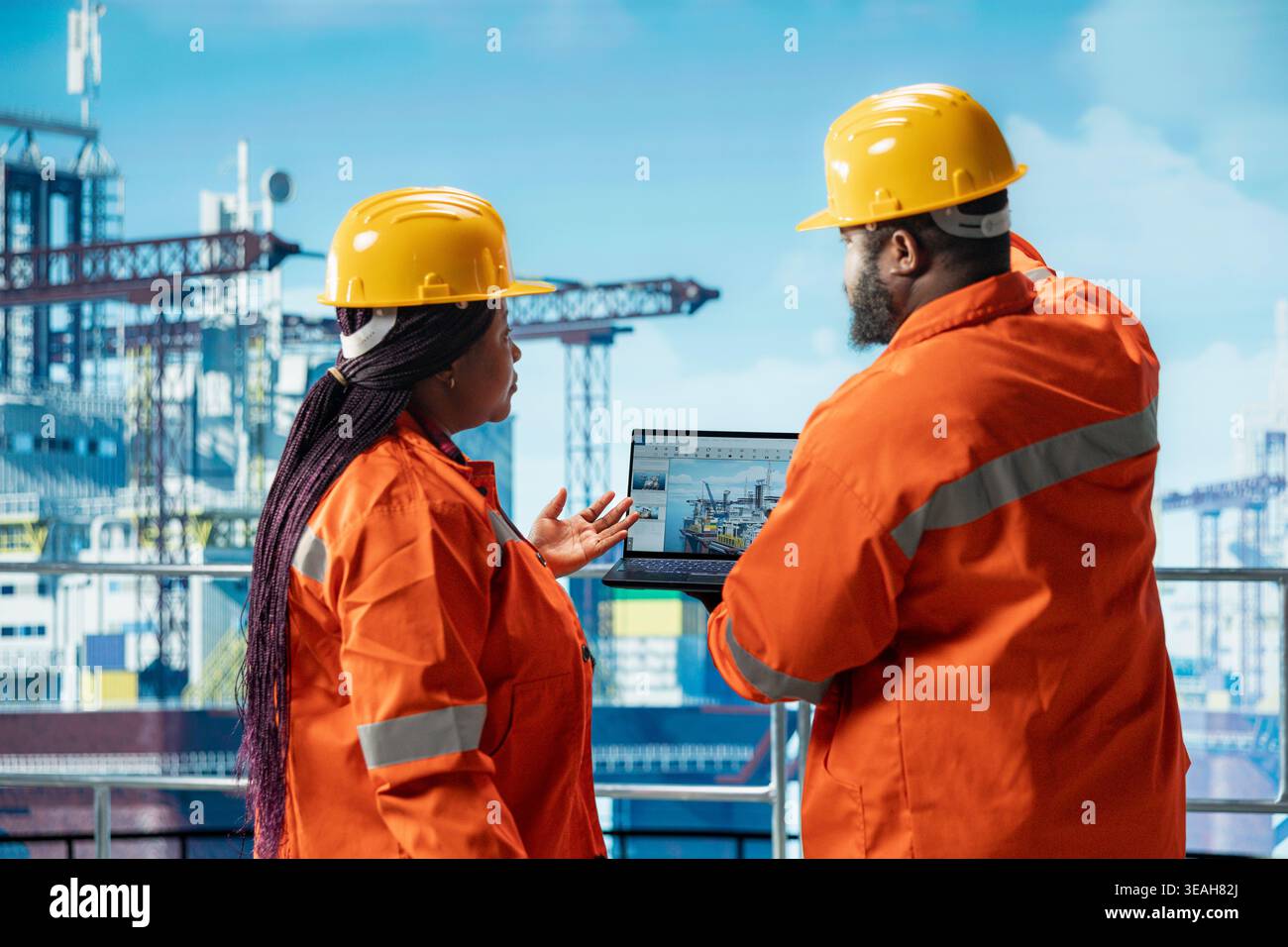 Offshore-Plattformingenieure, die Brainstorming durchführen und mithilfe eines Laptop-Programms Gerätekennzahlen überwachen. Mitarbeiter von Bohrkähnen in afroamerikanern kalibrieren das Gerät mit dem Asset Management-System auf dem Notebook Stockfoto