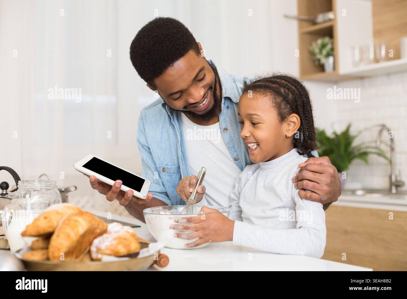 Vater und Tochter machen Gebäck, mit Rezept von digitalen Tablet Stockfoto