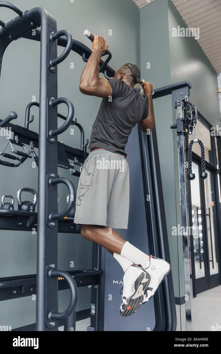 Mann, Der Pullups Auf Einem Metallgerät Macht, Intensives Oberkörpertraining, Fitnessumgebung, Muskuläres Engagement, Kreidete Hände, Sportliche Shorts Mit Konzentriertem Ausdruck Stockfoto