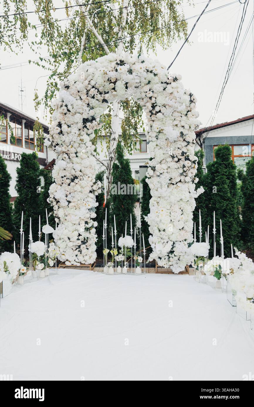 Üppiger Dekorationsbogen Mit Lebendigen Weißen Blüten Und Grünem Laub. Exquisites Blumengestell Mit Üppigen Weißen Blumen Und Grün Stockfoto