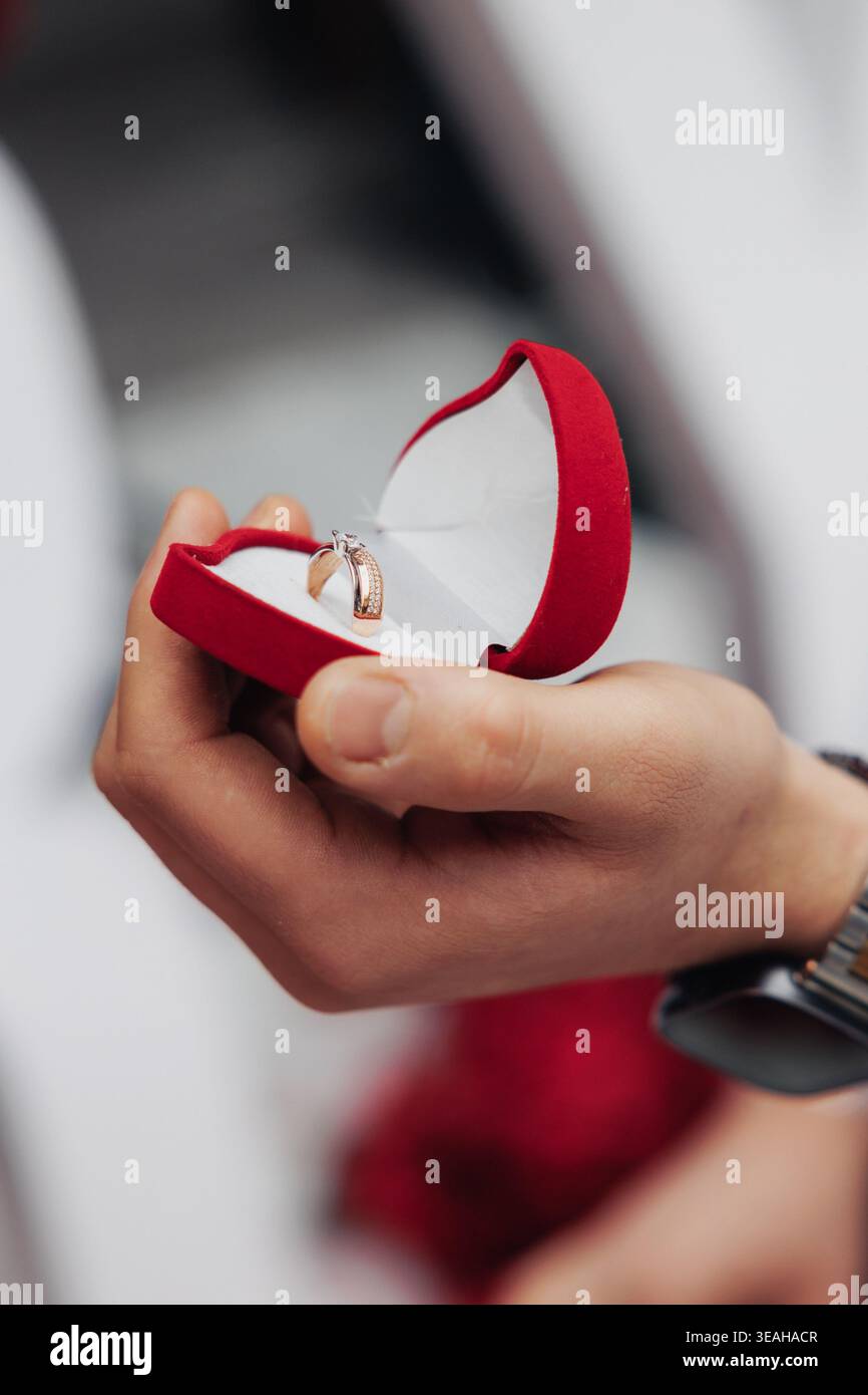 Hände Präsentieren Ring In Sanftem Licht. Nahaufnahme Von Gestenopfer Ring Mit Hintergrund. Detaillierte Ansicht Des Handopfer-Rings Vor Strukturiertem Hintergrund Stockfoto