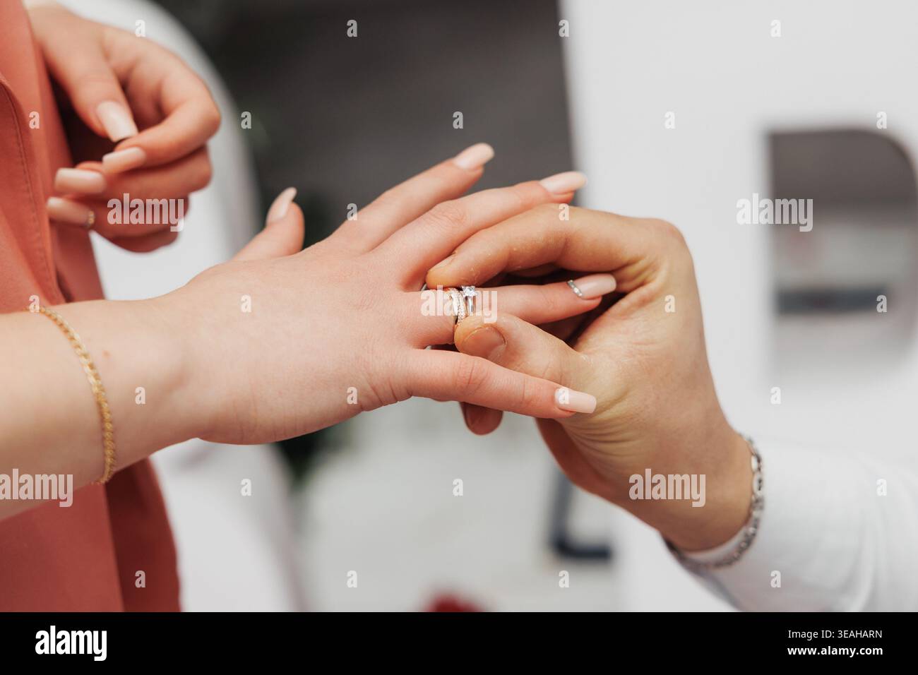Detaillierte Ansicht Des Bandes, Das Über Den Knöchel Gleitet. Warme Töne Heben Den Persönlichen Moment Der Ringanpassung Hervor. Sanfter Hintergrund Und Warme Farben Betonen Intimität Stockfoto