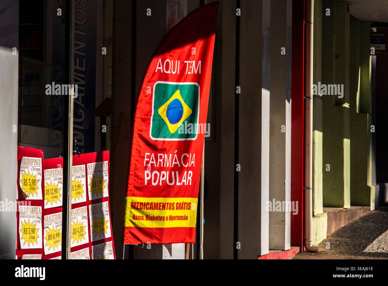 Marilia, SP, Brasilien, 22. April 2026: Eine rote Flagge und Banner der brasilianischen Popular Pharmacy, Programm in einer örtlichen Drogerie in der Innenstadt von Mari Stockfoto