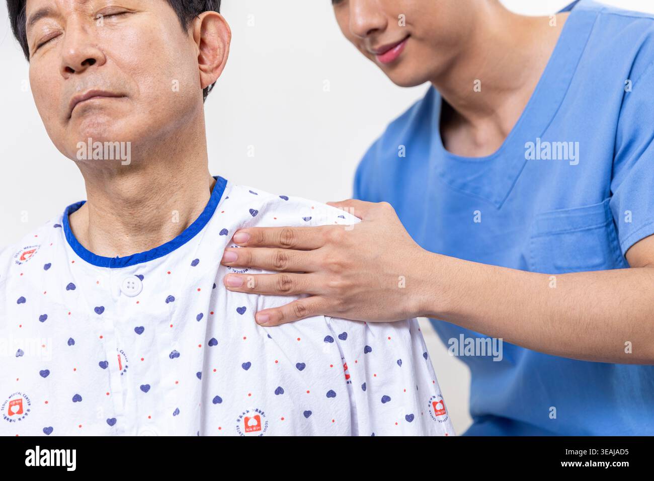 Eine Krankenschwester massiert sanft die Schulter eines Patienten im Krankenhaus. Stockfoto