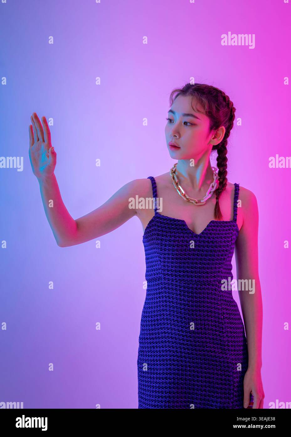 Eine junge Frau mit gestreckter Hand in einer Geste der Vorsicht oder des Zögerns, vor einem lebendigen und dynamischen Hintergrund. Stockfoto