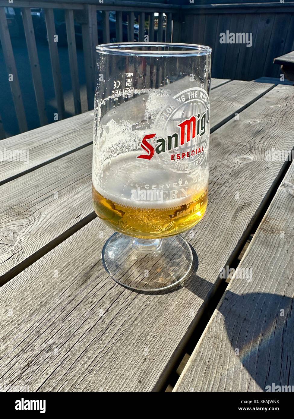 Weniger als ein halbes Pint San Mikguel Pils auf dem Tisch draußen Stockfoto