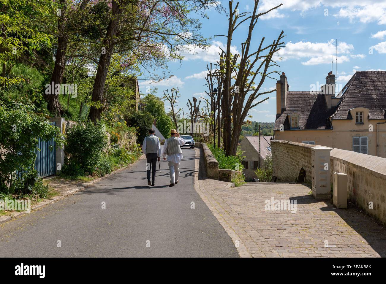Wunderschöne Straße in Auvers. Im Hintergrund ein Reiseleiter, der als der berühmte niederländische Maler Vincent Van Gogh gekleidet ist Stockfoto
