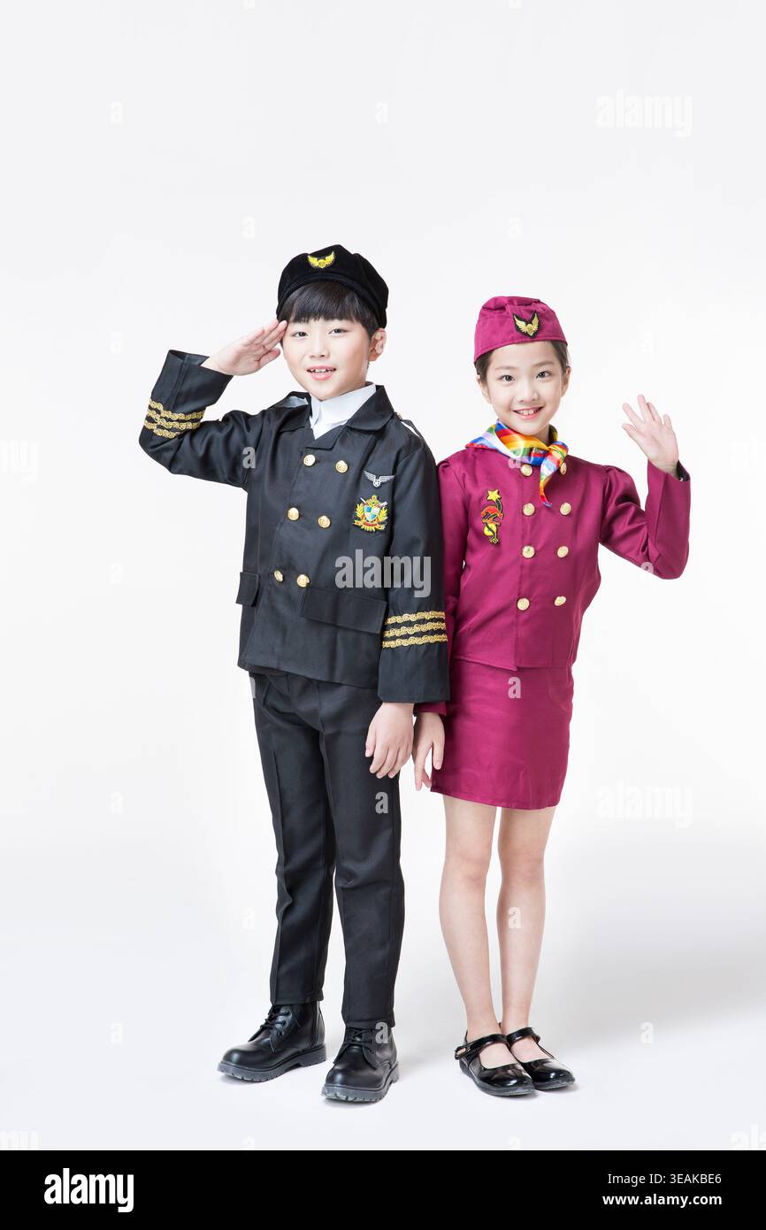 Zwei Kinder in Piloten- und Flugbegleiteruniformen, die zusammen in einem Studio stehen. Stockfoto