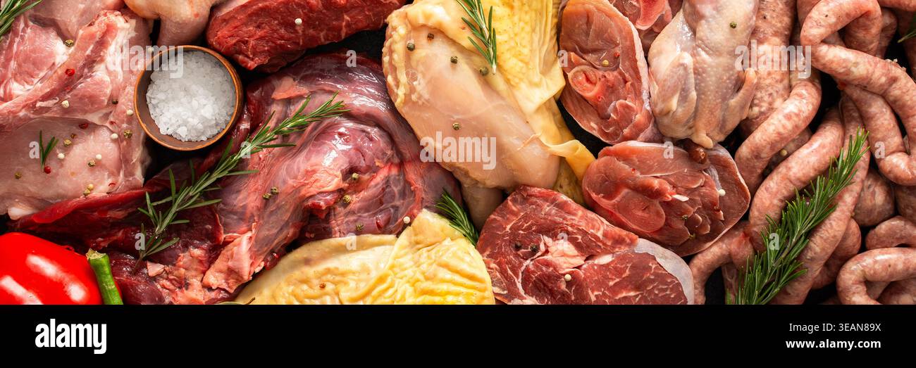 Verschiedene Fleischstücke sind auf dunkler Oberfläche angeordnet. Rindersteaks, Wachteln, Schweinefleischwürste, truthahn, Huhn, und Schweinefleisch sind zusammen mit Kräutern und spi vorhanden Stockfoto