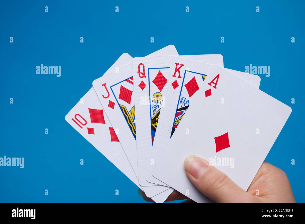 Eine Hand hält ein Standardspiel mit 52 Spielkarten, wobei die oberste Karte die Pikenkönigin ist. Stockfoto