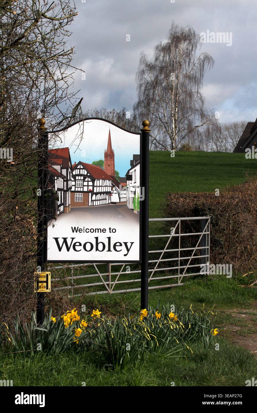 Willkommen in Weobley, Dorfschild, Hereforshire, Großbritannien. Mit Frühlingsblühenden Narzissen. Stockfoto