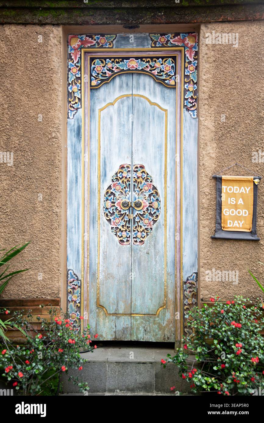 Verzierte blaue Holztür mit komplizierten traditionellen Mustern in einer strukturierten Wand Stockfoto