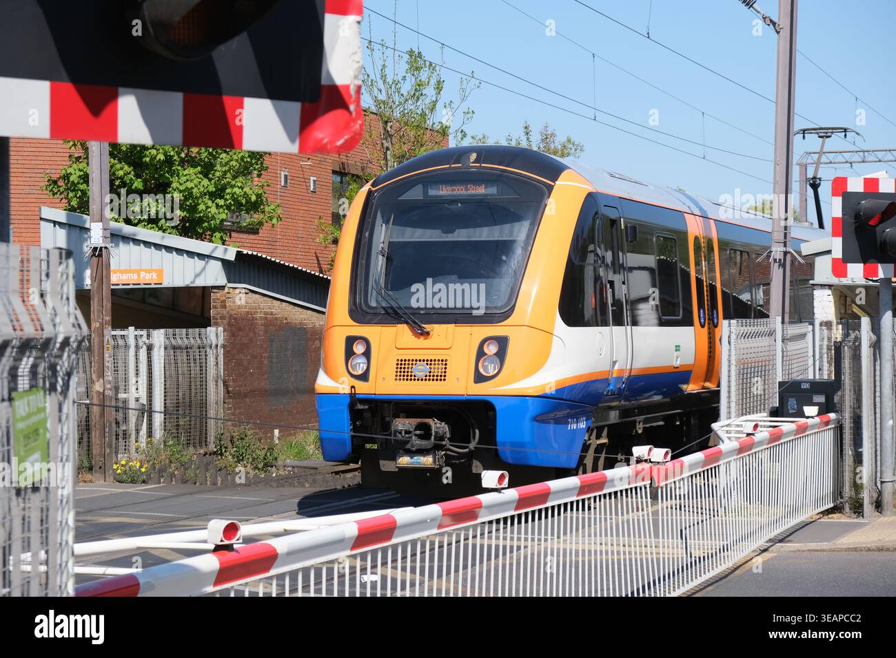 Ein London Overground-Zug überquert einen Bahnübergang, wenn er den Bahnhof Highams Park im Nordosten Londons verlässt Stockfoto