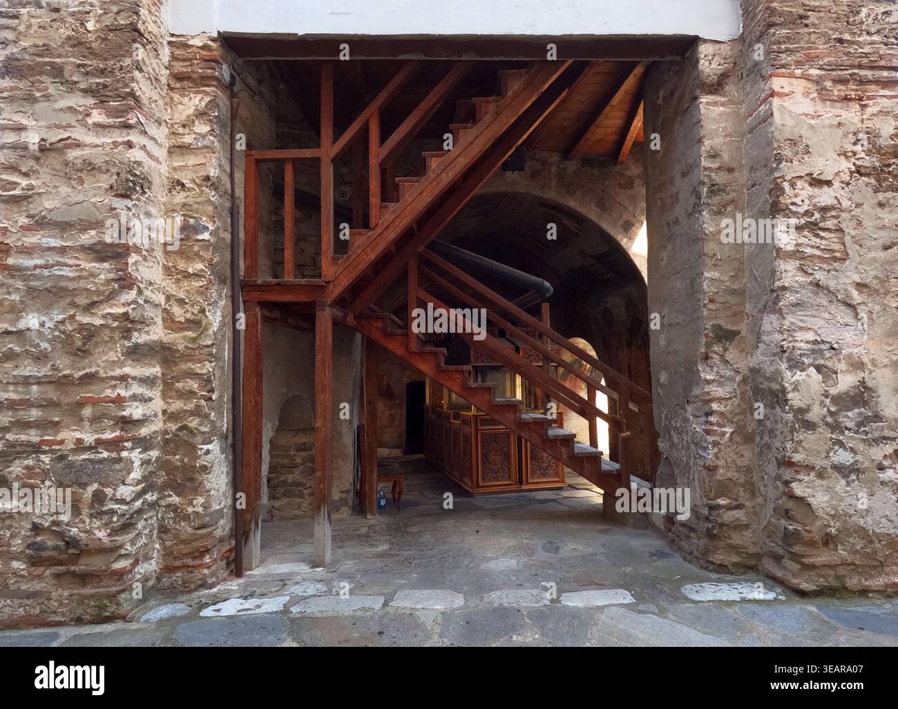 Traditionelle Holztreppe im Kloster Bachkovo mit Mauern aus Stein und Backstein, Bögen und Innenhofdetails in historischem klösterlichem Ambiente. Stockfoto