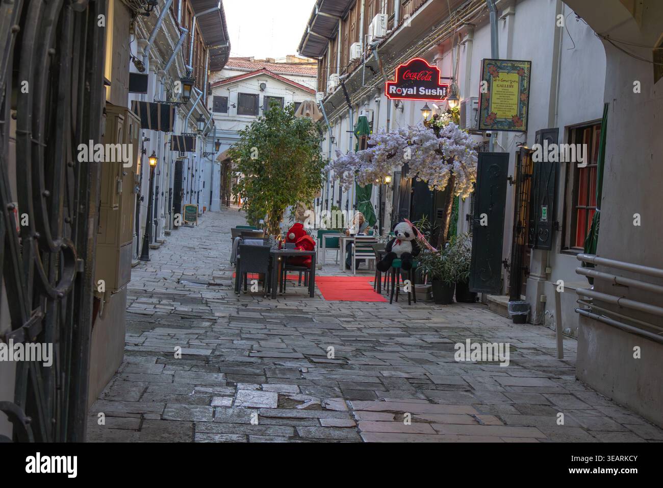 Enge gepflasterte Gasse in der Altstadt von Bukarest mit Cafés im Freien mit dekorativen Panda Plüschspielzeugen und Neonschildern - Bucuresti, Rumänien - M Stockfoto