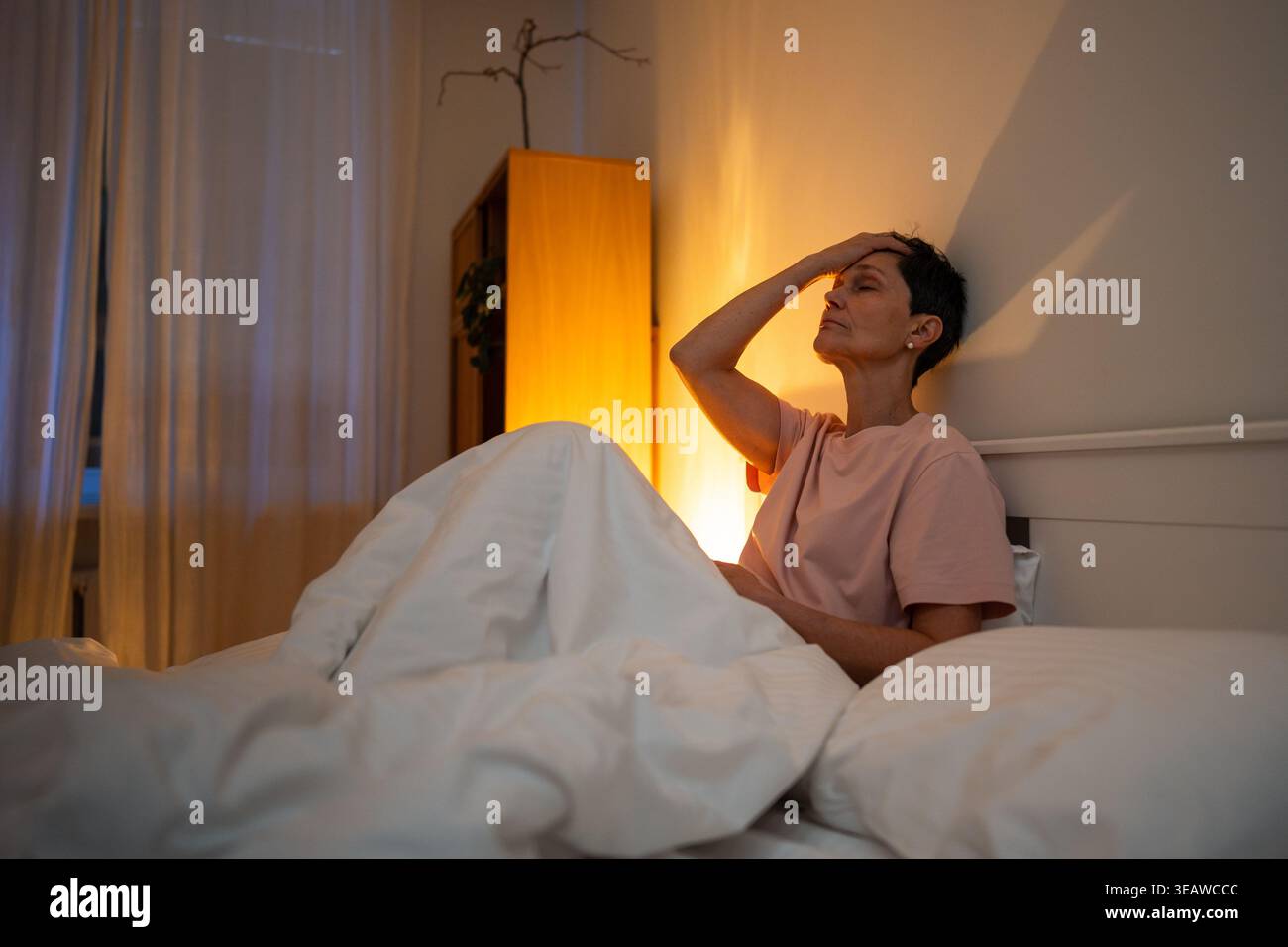 Erschöpfte, nachdenkende Seniorin mit Schlaflosigkeit Schlafstörung im Bett sitzend mit müdem Ausdruck. Stockfoto
