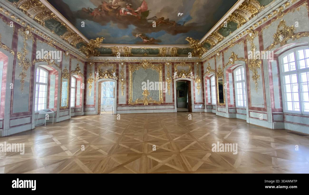 Geräumiger barocker Palastsaal im Schloss Rundale, Lettland, mit aufwendigen vergoldeten Verzierungen, bemalter Deckenfresko und großen Fenstern Stockfoto