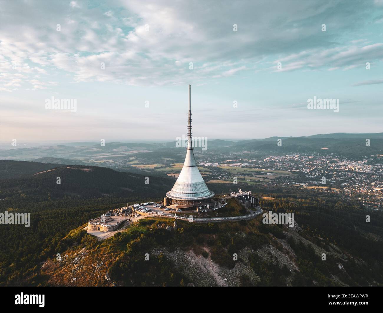 Das Jested Mountain Hotel, eingebettet in Liberec, bietet moderne Architektur vor einem malerischen Sonnenuntergang. Die Szene fängt die einzigartige Silhouette des Hotels mit der umliegenden Landschaft ein. Stockfoto