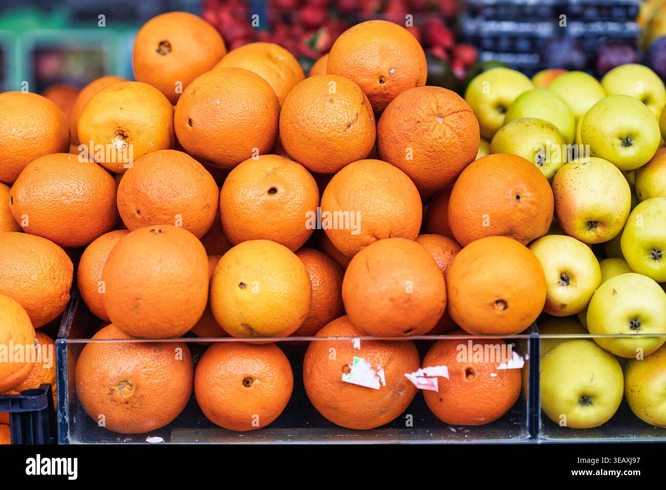Frische Orangen und grüne Äpfel stapeln sich auf einem lebhaften batumi-Obstmarkt, farbenfrohe Produkte mit nahrhaften, biologischen Zitrusfrüchten und Apfeln Stockfoto