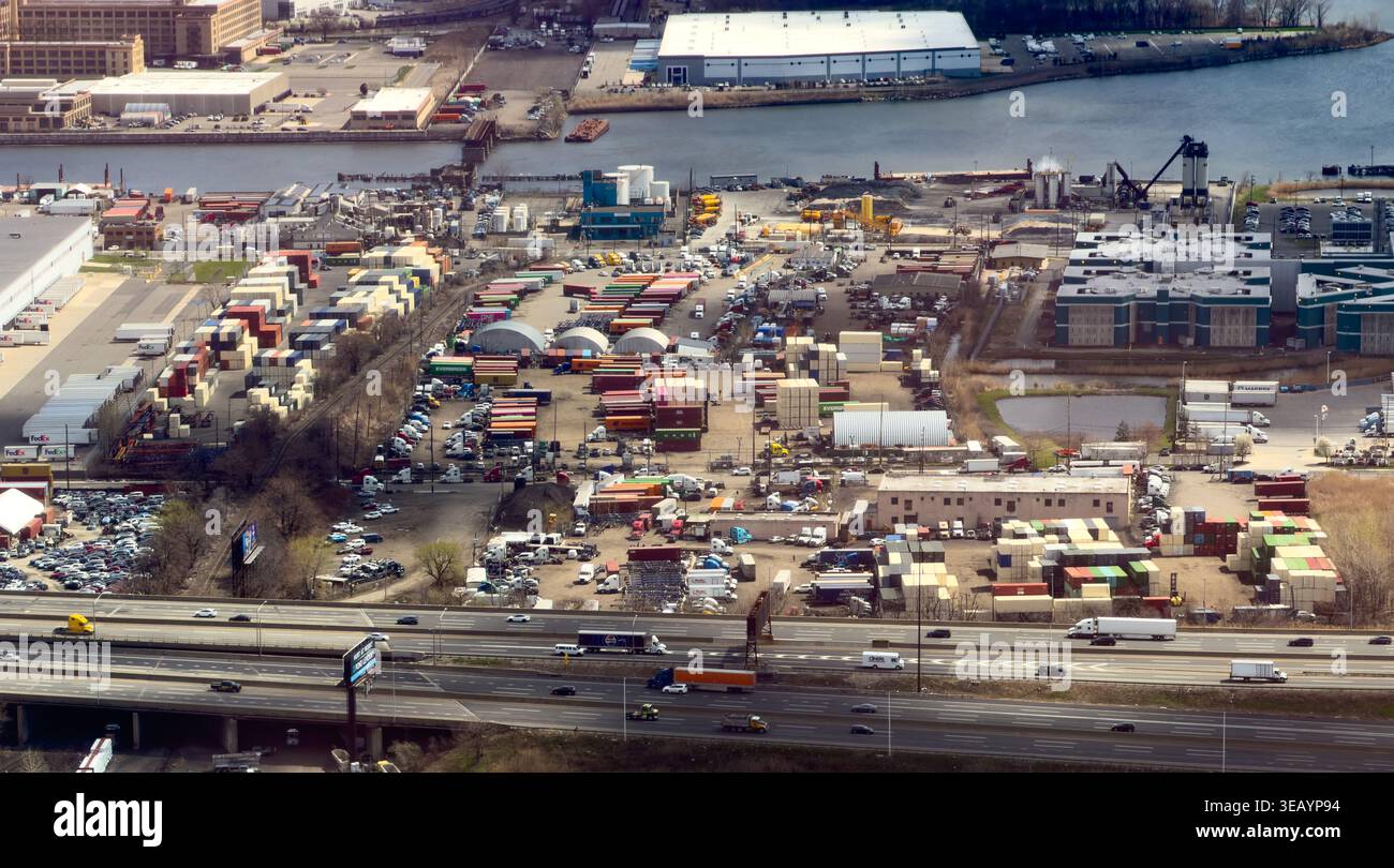 Aus der Vogelperspektive eines belebten Industrieviertels mit einem Netz von Straßen und Containern in der Nähe einer Wasserstraße, Elizabeth, New Jersey, USA. Stockfoto