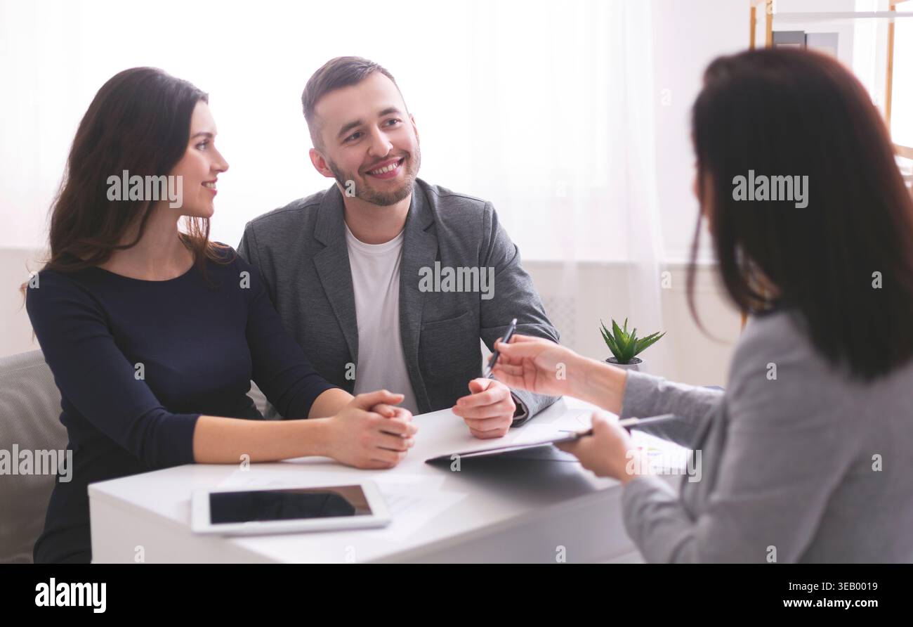 Junges Paar diskutiert Pläne mit Finanzberater in modernem Büroumfeld Stockfoto