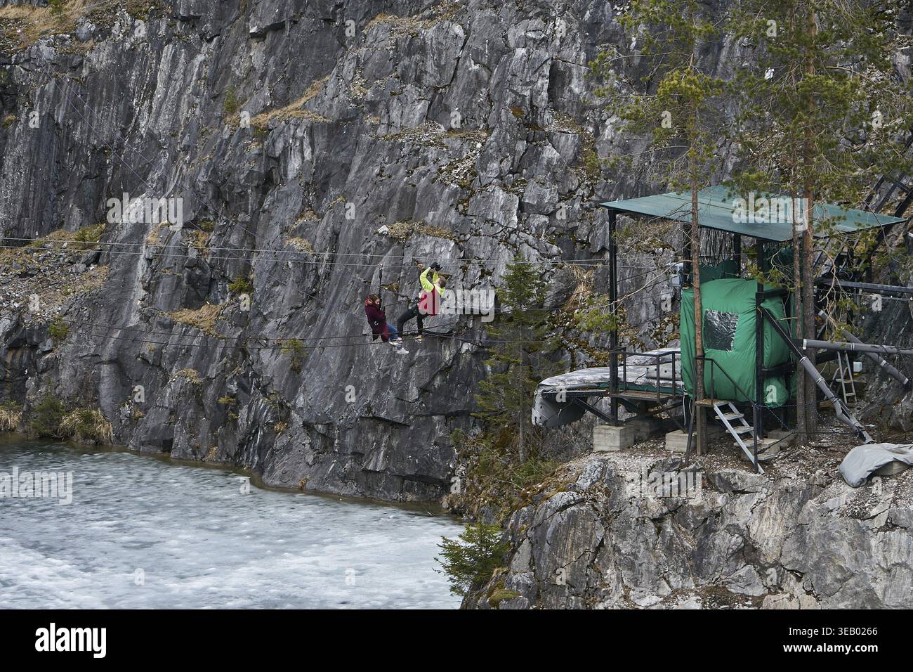 Zwei Personen Seilrutschen im Ruskeala Mountain Park. Frau und Mann auf einer Seilrutsche über einem Fluss, verkörpern Abenteuertourismus für das Reisemagazin. Karelien, R Stockfoto