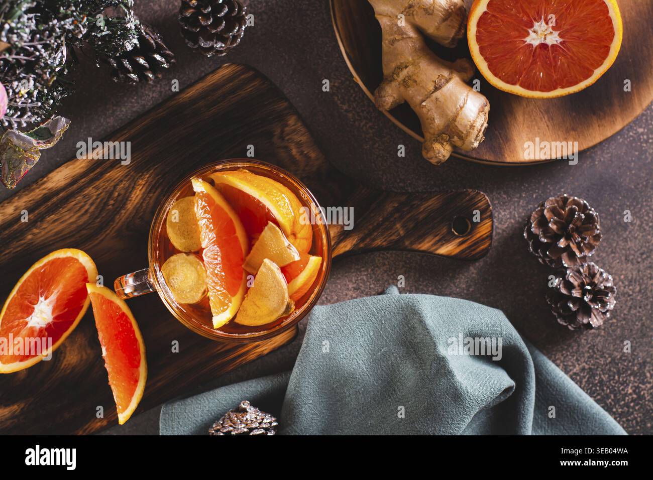 Duftender Tee mit Orangen- und Ingwerstücken in einer Tasse auf dem Tisch Stockfoto