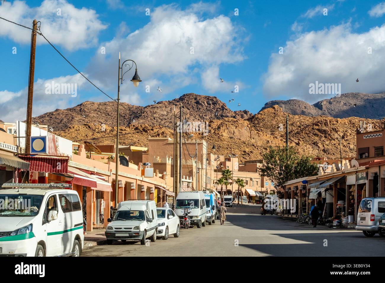 Stadtstraße mit kleinen lokalen Geschäften, Verkehr von Autos und Motorrädern, Bewohner und blauem Himmel. Gelegen im Anti-Atlas-Gebirge, in der Agadir Re Stockfoto