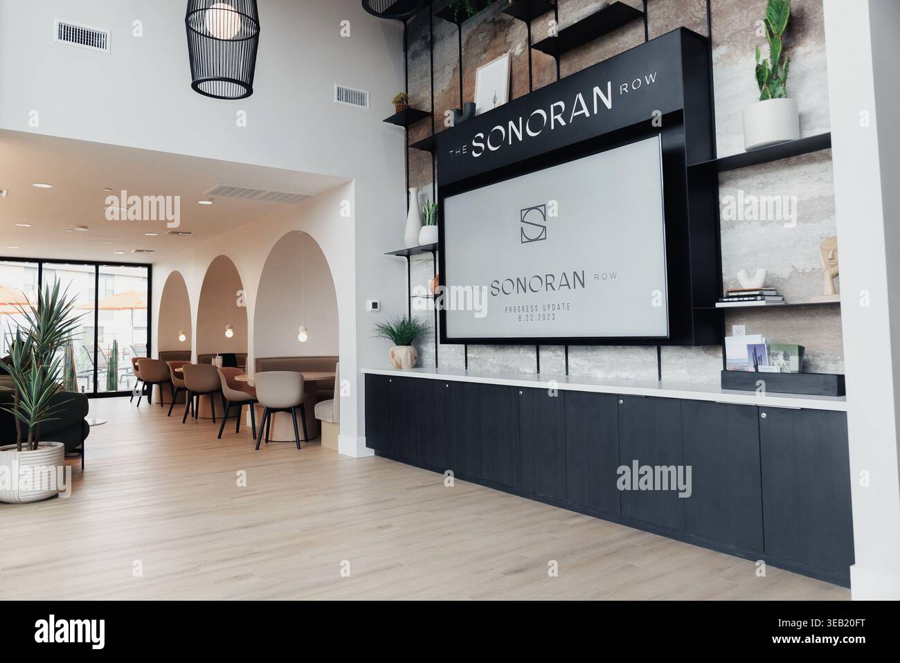 Heller, Moderner Rezeptionsbereich Mit Schreibtisch, Sanftem Natürlichem Licht, Großer Schilderwand Mit Logo, Langer Schwarzer Rezeptionstheke, Topfpflanzen, Holz Stockfoto