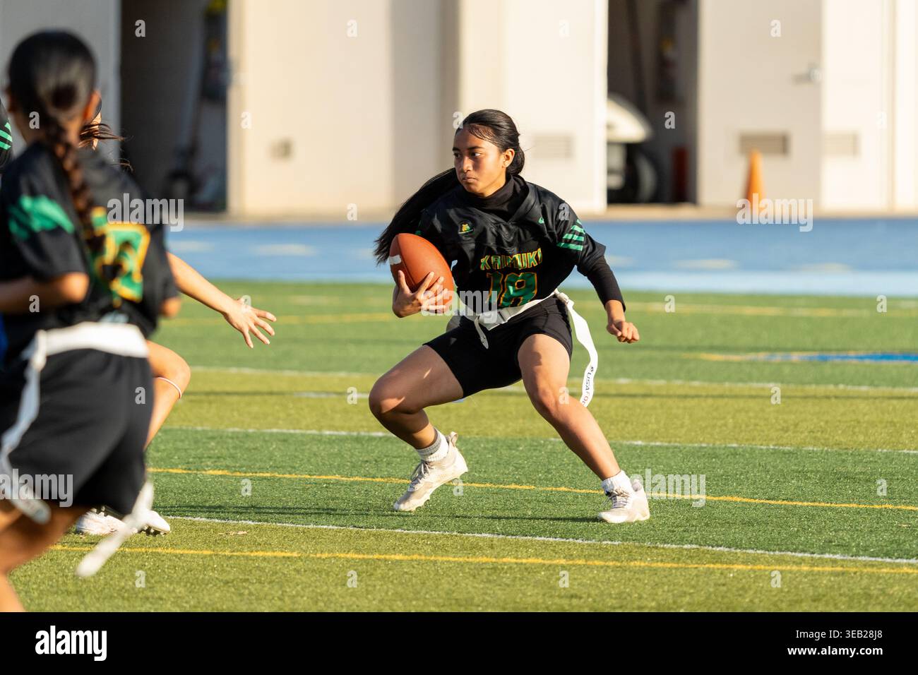 Flag Football – weibliche Athletin, die den Ball als Verteidigerin während des Spiels der Kaiser gegen Kaimuki Junior Varsity High School spielt Stockfoto