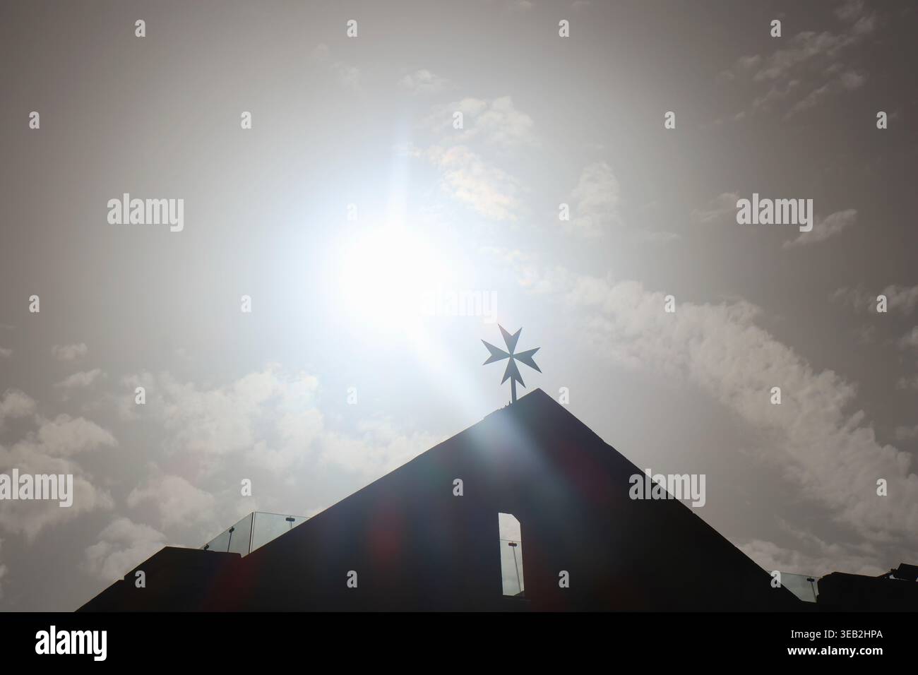 Silhouette eines maltesischen Kreuzes auf einer Kirche in Valletta, Malta, mit der Sonne dahinter. Stockfoto