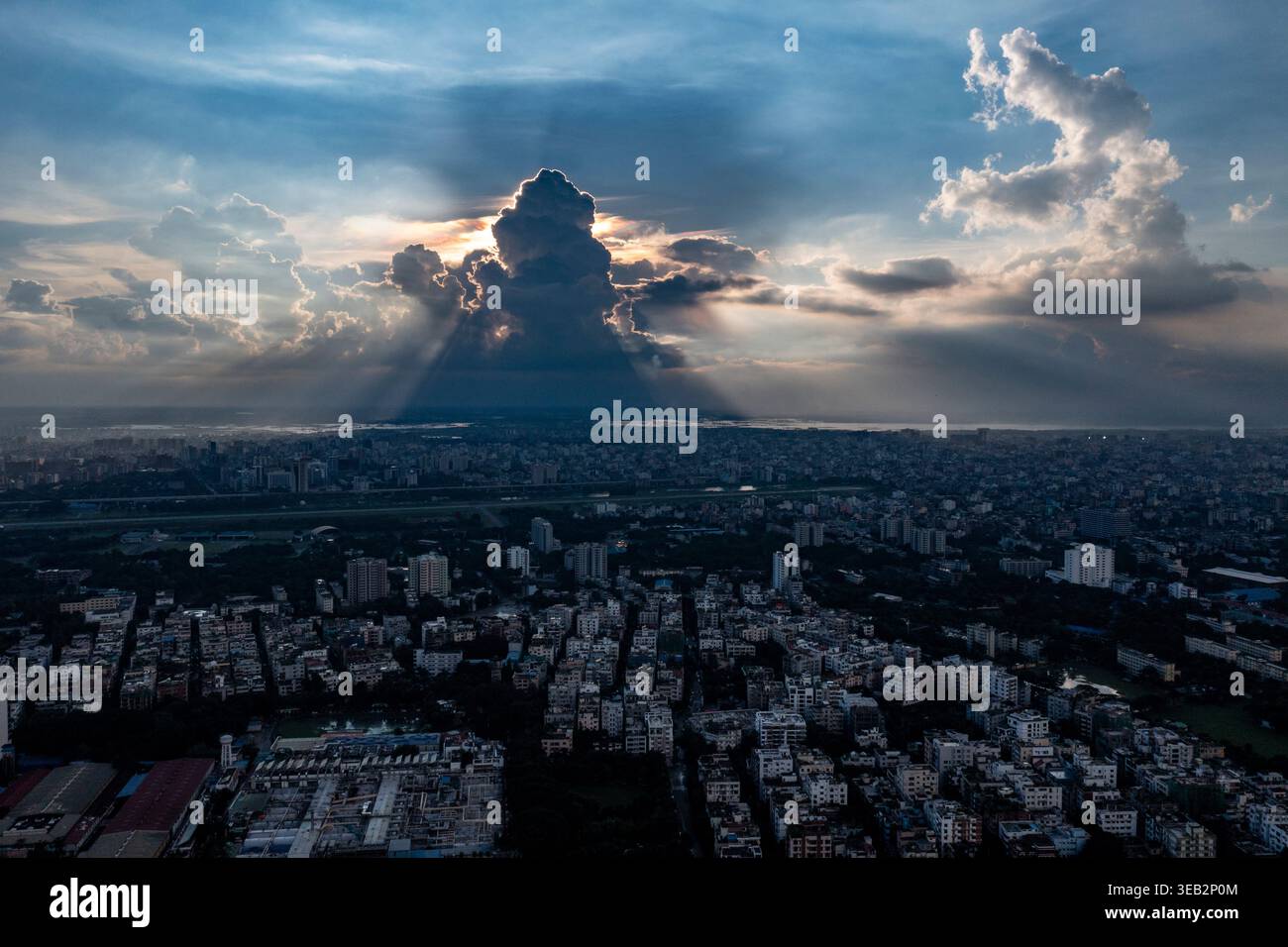 Die Sonne geht über einer Wolkendecke auf und wirft weiche Schatten über Dhaka Stadt in einer ruhigen Drohnenperspektive. Bangladesch Stockfoto