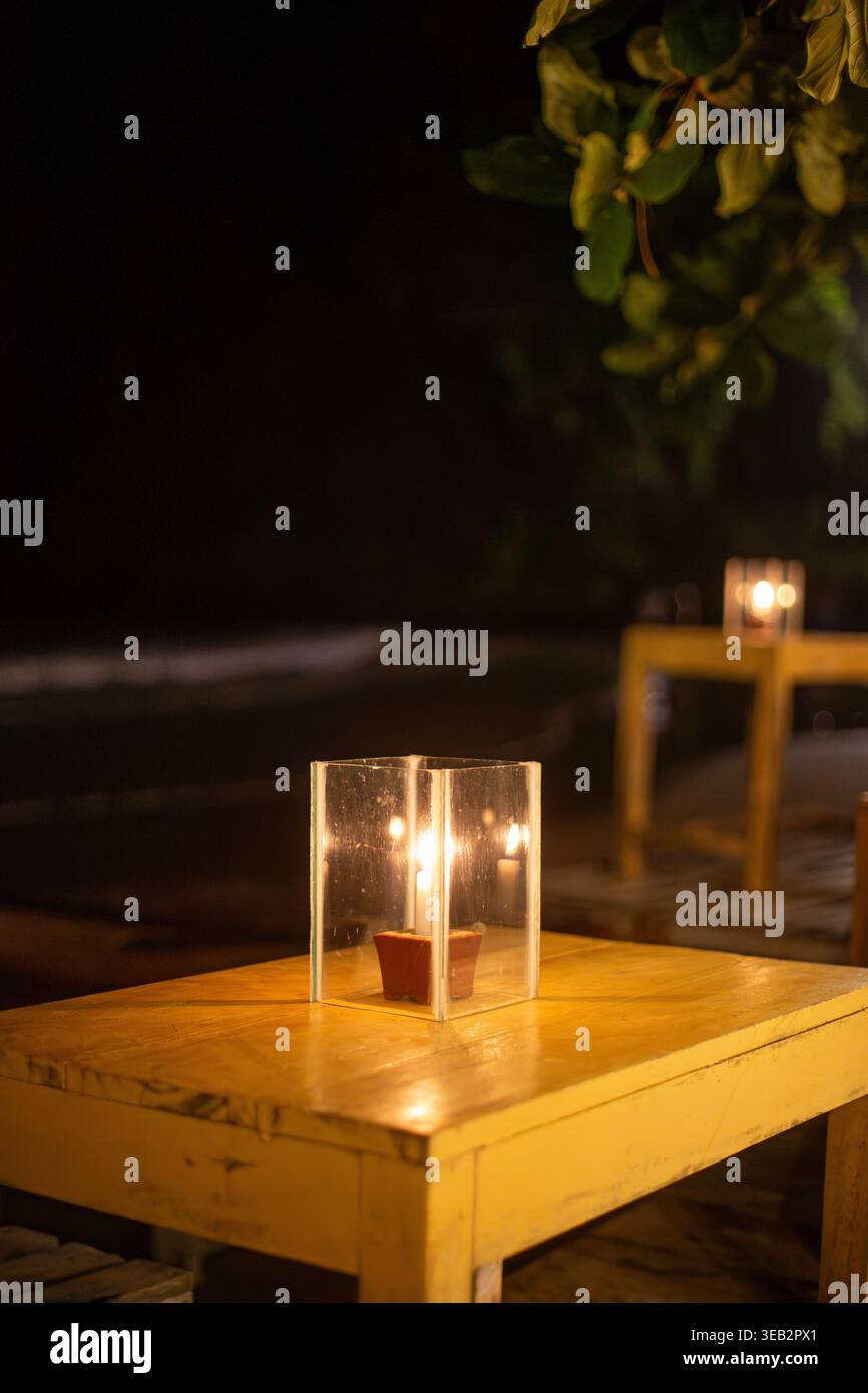 Kleine Kerze im Glashalter auf einem Holztisch in einem tropischen Strandrestaurant in Sri Lanka Stockfoto