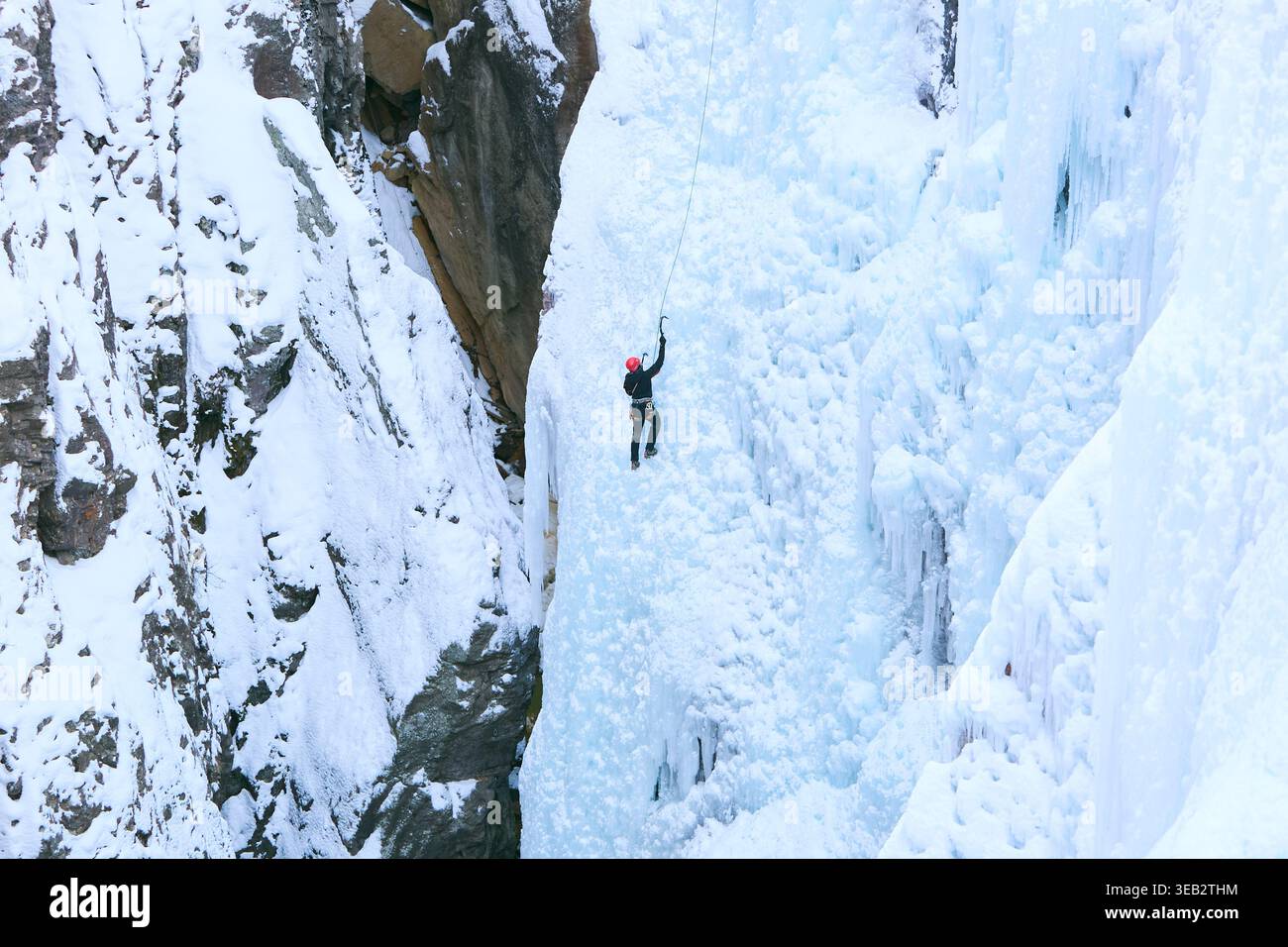 Bergsteiger, die den gefrorenen Wasserfall in der Winterlandschaft aufsteigen Stockfoto