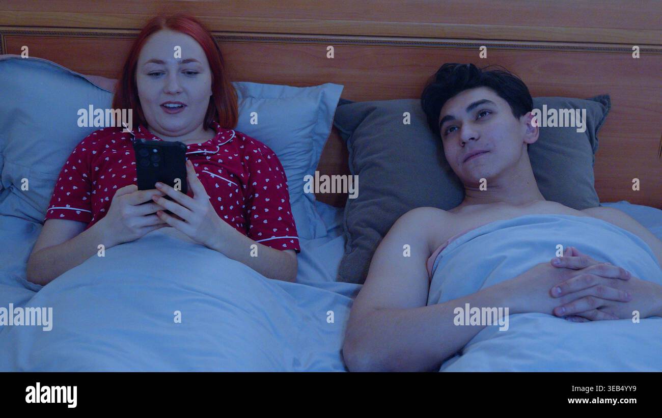 Zwei Personen, die nachts im Bett Mobiltelefone benutzen Stockfoto