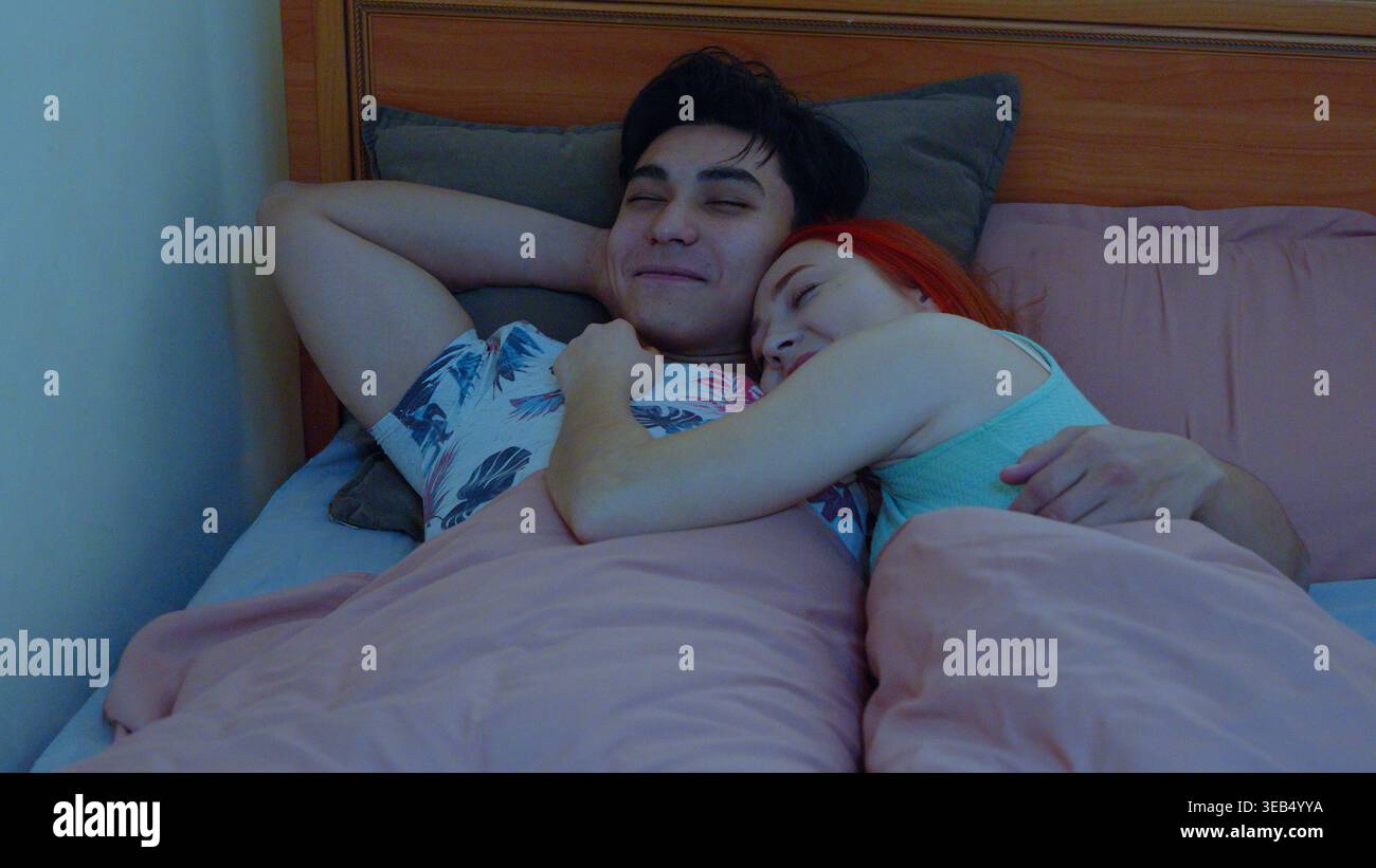 Mann und Frau benutzen Telefone, während sie im Bett ruhen Stockfoto
