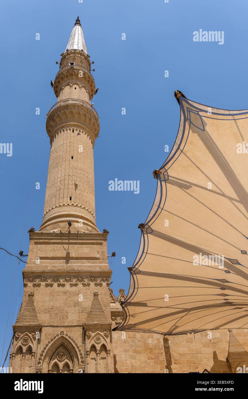 Blick auf das hohe Steinminarett der Imam Al-Hussein Moschee und ein großes architektonisches Baldachin unter einem klaren blauen Himmel in Kairo, Ägypten. Stockfoto