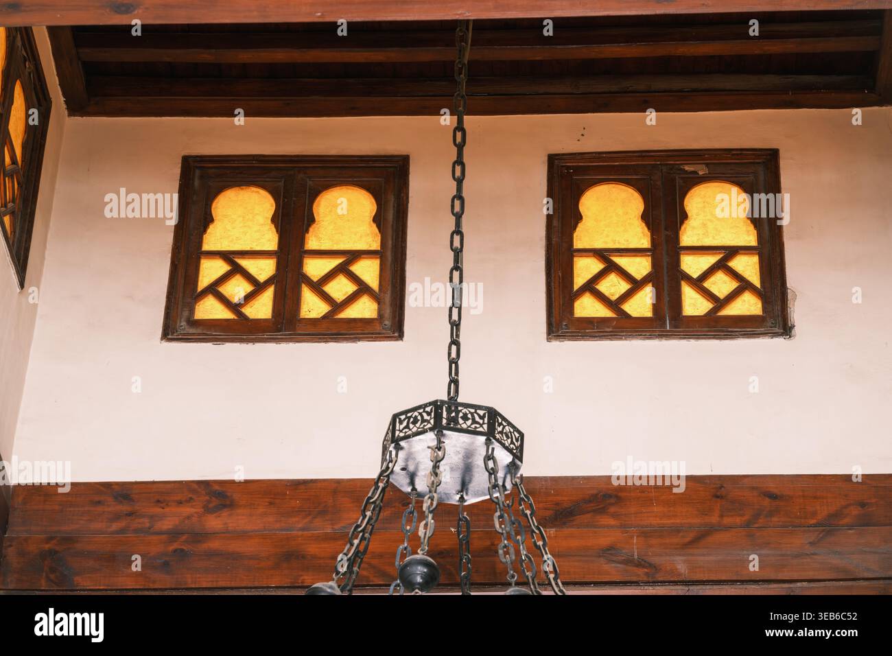 Blick auf die traditionellen Bogenfenster mit geometrischem Gitter und einem hängenden Metallleuchter in der historischen Al-Azhar Moschee Kairo, Ägypten. Stockfoto