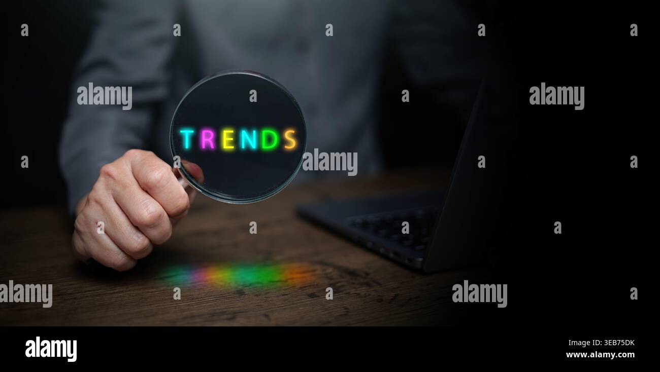 Trendkonzept mit einer Lupe über leuchtendem Neontext als Symbol für digitale Marktforschung, Zukunftsprognosen und kreative Strategie Stockfoto