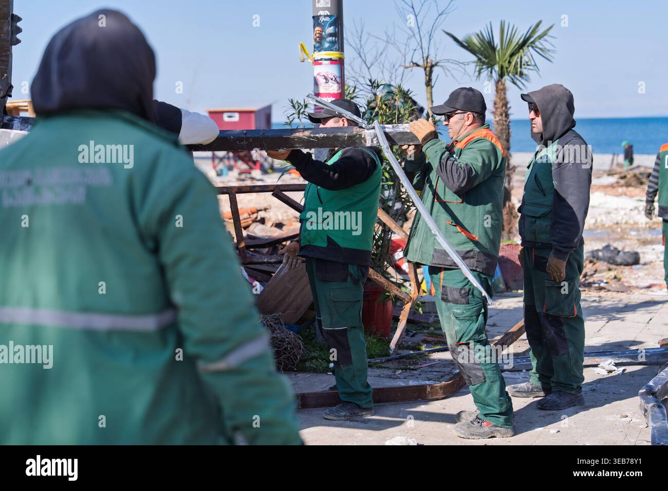 Batumi, georgien 21. april 2026: Bauarbeiter in grünen Uniformen demontieren provisorische Bauwerke und entfernen Trümmer vom Strand in batu Stockfoto